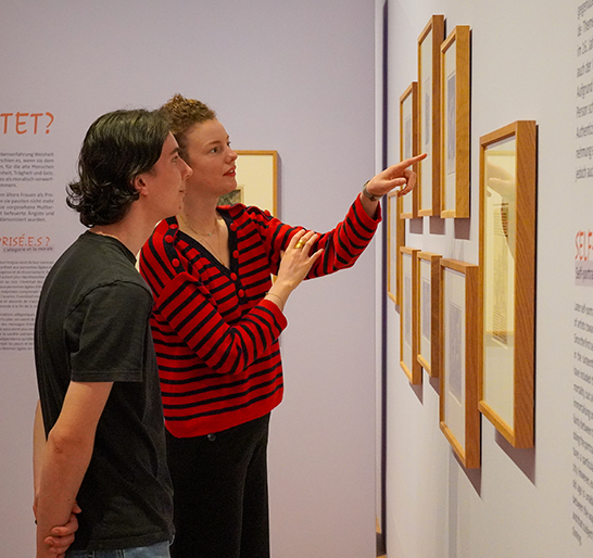 Eine Person steht vor einer Mutter-Kind-Gruppe und benutzt die Augustinermuseum-App auf dem Smartphone.