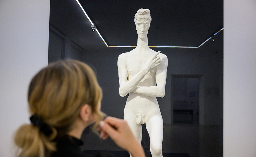 Eine Person betrachtet die Skulptur "Der Jüngling" von Julius Bissier.