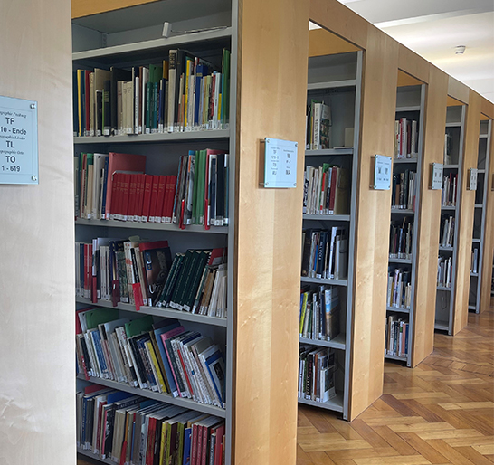 Mehrere Regalreihen sind mit Büchern gefüllt.